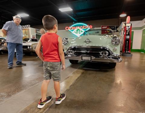 child and adult looking at old cars