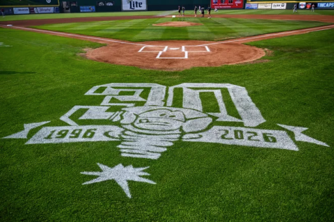 A green baseball field with a painted Lansing Lugnuts logo